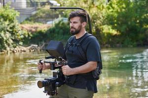 en professionellt utrustad kameraman skjuter i de vatten omgiven förbi skön natur. foto