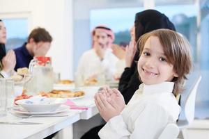 liten muslim pojke bön- med familj innan iftar middag foto