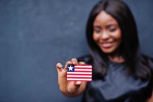 stolt till vara liberian. afrikansk kvinna håll små Liberia flagga i händer. foto