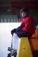 barn is hockey spelare på bänk foto