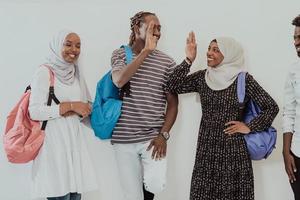 Foto av en grupp av Lycklig afrikansk studenter talande och möte tillsammans arbetssätt på läxa flickor bär traditionell sudansk muslim hijab