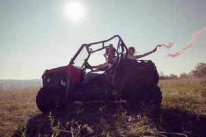 upphetsad människor har roligt njuter skön solig dag innehav färgrik facklor medan körning en av väg buggy bil foto