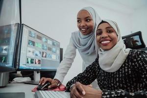 vänner på de kontor två ung afro amerikan modern muslim affärskvinna bär scarf i kreativ ljus kontor arbetsplats med en stor skärm foto