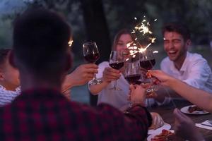 vänner toasting röd vin glas medan har picknick franska middag fest utomhus- foto