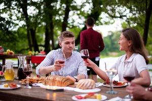 Lycklig vänner har picknick franska middag fest utomhus- foto