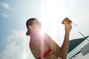 skön asiatisk blanda lopp solbränd hud kvinna promenad längs lyx yachter i djup hav, röd bikini solglasögon flicka Framställ som mode modell i dockning pir under sommar blå himmel i semester Semester foto