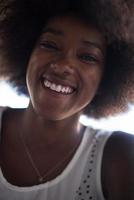närbild porträtt av en vacker ung afroamerikansk kvinna som ler och tittar upp foto