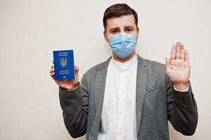 europeisk man i formell ha på sig och ansikte mask, visa ukraina pass med sluta tecken hand. coronavirus låsning i Europa Land begrepp. foto