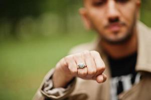 eleganta kuwaiti man på dike täcka visar en ringa på hans hand. foto