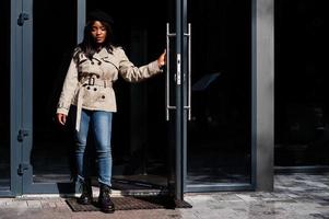 modern afrikansk amerikan kvinna ha på sig basker och täcka stående mot dörr. foto