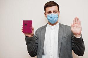 europeisk man i formell ha på sig och ansikte mask, visa cypern pass med sluta tecken hand. coronavirus låsning i Europa Land begrepp. foto