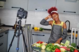 afrikansk amerikan kvinna filmning henne blog utsända handla om friska mat på Hem kök. foto