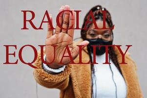 ras- jämlikhet. afrikansk amerikan kvinna, ha på sig svart ansikte mask visa sluta hand tecken. foto