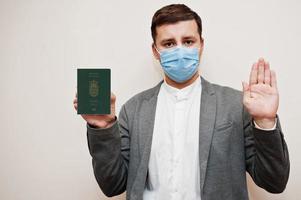 europeisk man i formell ha på sig och ansikte mask, visa faroe öar pass med sluta tecken hand. coronavirus låsning i Europa Land begrepp. foto