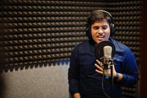 ung asiatisk sångare man med mikrofon inspelning låt i spela in musik studio. foto