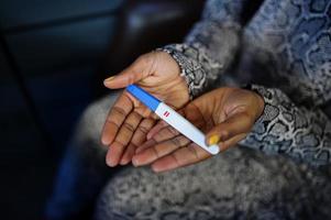afrikansk amerikan kvinna känsla överraskning håll graviditet testa. foto