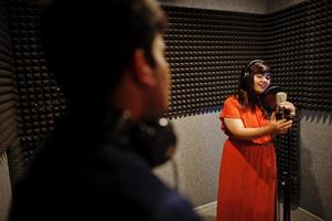 ung asiatisk duett sångare med mikrofon inspelning låt i spela in musik studio. foto