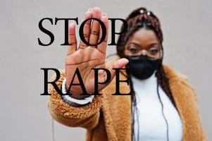 sluta våldta. afrikansk amerikan kvinna, ha på sig svart ansikte mask visa sluta hand tecken. foto