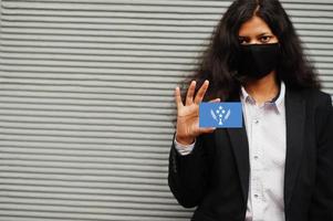 asiatisk kvinna på formell ha på sig och svart skydda ansikte mask håll kosrae flagga på hand mot grå bakgrund. coronavirus på Land begrepp. foto