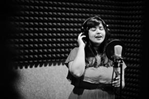 ung asiatisk sångare med mikrofon inspelning låt i spela in musik studio. foto
