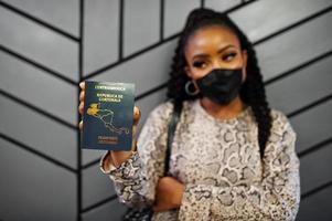afrikansk amerikan kvinna bär svart ansikte mask visa guatemala pass i hand. coronavirus i Amerika Land, gräns stängning och karantän, virus utbrott begrepp. foto