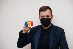 europeisk man ha på sig svart formell och skydda ansikte mask, håll moldavien flagga kort isolerat på vit bakgrund. Europa coronavirus covid Land begrepp. foto