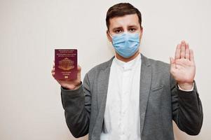 europeisk man i formell ha på sig och ansikte mask, visa bulgarien pass med sluta tecken hand. coronavirus låsning i Europa Land begrepp. foto