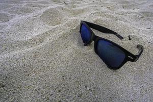 ensam solglasögon liggande på en sandig strand foto