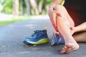 löpare vidrör smärtsam vriden eller bruten fotled. idrottare löpare träning olycka. sport löpning ankel stukad stukning orsaka skada knä. och smärta med benben. fokusera röda ben på för att visa smärta. foto