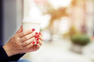 kvinna hand innehav papper kopp av ta bort dricka kaffe på stad bakgrund. Plats plats för din text eller logotyp. foto