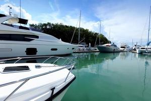 många lyx yachter flyta på kristall klar hav i marina bukt klubb, dyr privat båt stanna kvar lugna i dockning pir under sommar blå himmel grön hav foto