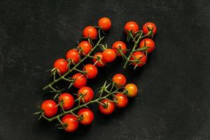 topp se av färsk körsbär tomater på svart bakgrund. friska mat, mogen grönsaker foto