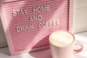 rosa kaffe kopp och qoute stanna kvar Hem och dryck kaffe. själv isolering och karantän kampanj till skydda själv och spara liv. foto