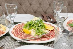 stänga upp av italiensk antipasto - carpaccio med ruccola, parmesan och citron. medelhavs aptitretare. foto