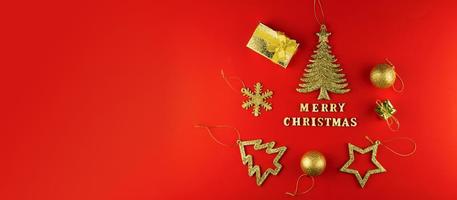 festlig hälsning kort. glad jul text på röd papper med gyllene glittrande leksaker. baner. foto