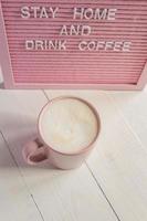 rosa kaffe kopp och qoute stanna kvar Hem och dryck kaffe. själv isolering och karantän kampanj till skydda själv foto
