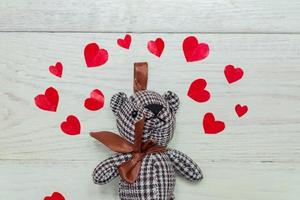 teddy Björn bland röd papper hjärtan på trä- bakgrund. hälsning kort med kopia Plats för design foto