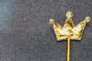 gyllene magi pinne från paljetter i krona form på svart glitter bakgrund. kreativ platt lägga stänga upp foto