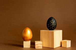 trendig påsk bakgrund. gyllene och svart målad ägg stå på trä- kuber, pallplatser på brun bakgrund. foto