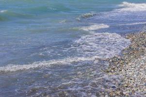 stenkustlinje. havsstrand med genomskinligt vatten och små stenar foto