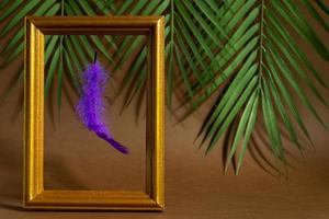 årgång gyllene fotoram med neon lila fjäder på tropisk löv bakgrund. trendig begrepp, levitation. foto