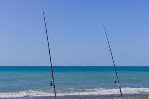 två fiske stavar på hav strand. fiske turism och semester begrepp foto