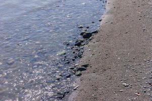 stenkustlinje. havsstrand med genomskinligt vatten och små stenar foto