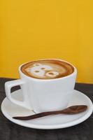 en kopp av kaffe latte konst tycka om Björn ansikte på gul bakgrund foto