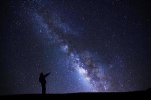 en man är stående pekande på en ljus stjärna med mjölkig sätt galax och Plats damm i de universum foto