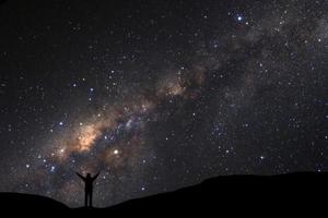 landskap med mjölkig sätt, natt himmel med stjärnor och silhuett av man stående på hög moutain foto