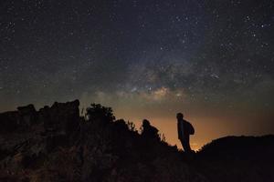 landskap med mjölkig sätt, natt himmel med stjärnor och silhuett av en stående man på doi luang chiang dao med thai språk topp punkt tecken. lång exponering fotografi.med spannmål foto