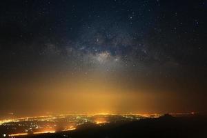 mjölkig sätt galax med stjärnor och Plats damm i de universum och stad ljus på phutabberk Phetchabun i thailand. foto