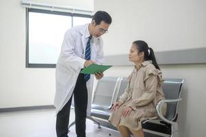 asiatisk läkare är arbetssätt i sjukhus , talande med sorg kvinna , medicinsk hälsa vård begrepp foto