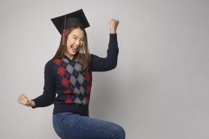 ung leende kvinna innehav gradering hatt, utbildning och universitet begrepp foto